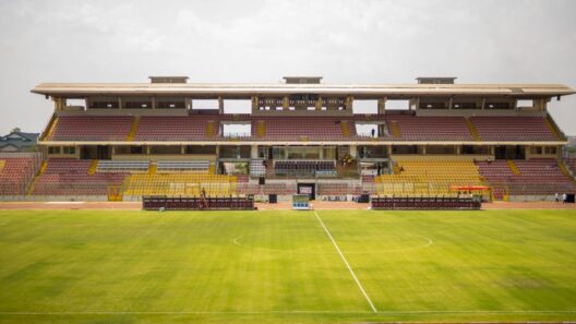 Estádio de futebol com bancadas vazias e relvado verde.