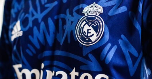 Vista de close-up de uma camisa de futebol azul do Real Madrid apresentando o logo e elementos de design da equipe.