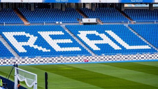 Área de assentos vazia no estádio do Real Madrid com 'REAL' em destaque em branco.