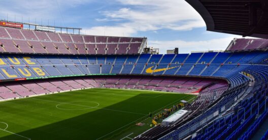 Estádio Camp Nou do FC Barcelona com as bancadas azuis e vermelhas e o relvado verde.