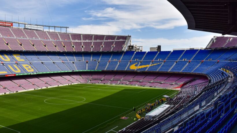 Estádio Camp Nou do FC Barcelona com as bancadas azuis e vermelhas e o relvado verde.