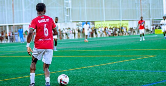 Foto de ação de um jogador de futebol durante uma partida em um dia claro e ensolarado.