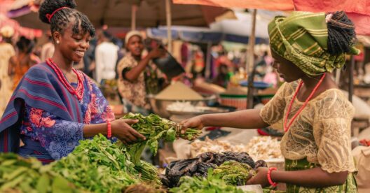 Duas mulheres a negociar produtos frescos num mercado africano.