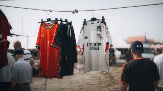 Camisolas de futebol do Milan e do Benfica penduradas numa corda, com pessoas ao fundo.