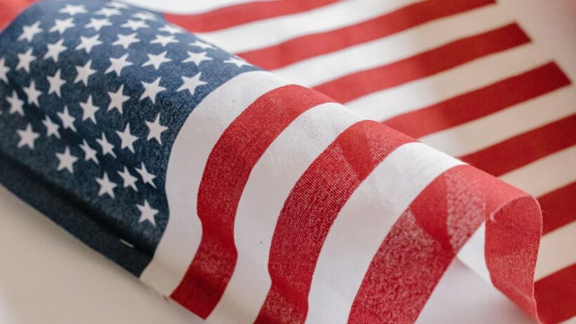 Um close-up detalhado do tecido da bandeira americana mostrando estrelas e listras em uma luz natural suave.
