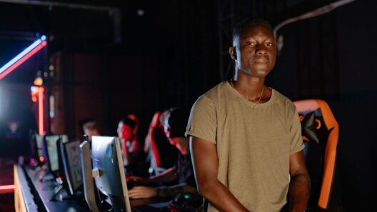 Jovem adulto num centro de jogos com computadores ao fundo.